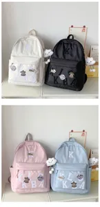 Detail view of multi-color school backpacks with letter patches and cute cloud pendants.