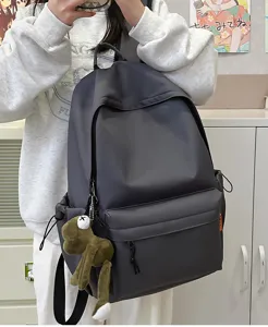 Dark grey casual backpack detail view, large capacity solid color school bag with cute frog pendant.