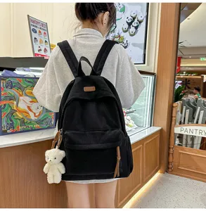 Black corduroy backpack with cute bear pendant, large capacity school bag for daily travel.