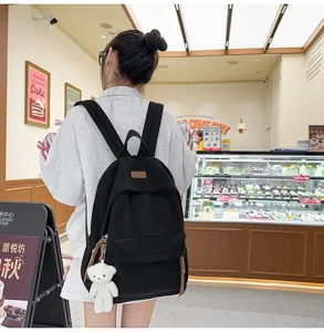 Stylish black corduroy school backpack with cute bear pendant, trendy daily casual travel bag.
