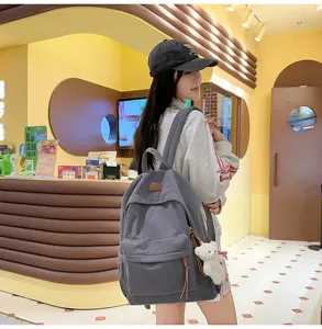 Grey corduroy backpack for women, casual school bookbag with cute bear pendant and large capacity.
