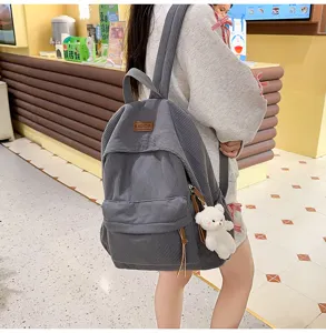 Grey corduroy backpack detail view featuring soft texture, front pocket and cute bear pendant.