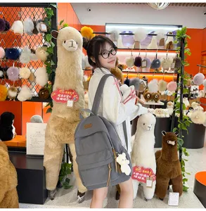 Grey corduroy backpack detailed with cute bear pendant, lifestyle shot in retail store showcase.