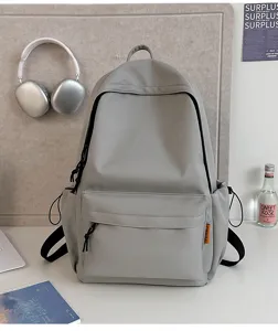 Detailed view of grey minimalist canvas backpack with front zip pocket and side slots.