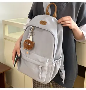 Casual canvas school backpack for students, stylish daily daypack with cute plush pendant.