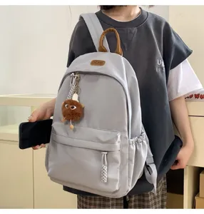 Grey canvas school backpack for students, casual daily daypack with cute plush pendant.