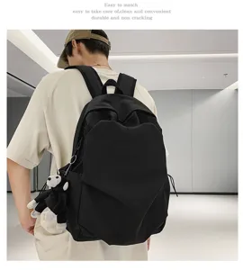 Minimalist black backpack with large capacity and cute monkey pendant for daily casual use.