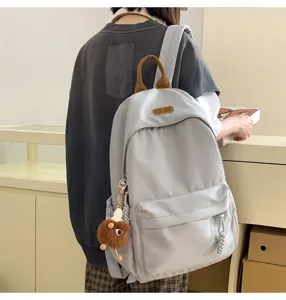 Casual light gray school backpack for women and students with front pocket and cute plush charm.