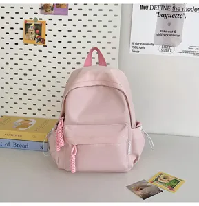 Pink mini backpack detail view, cute student school bag with front pocket and tassels.