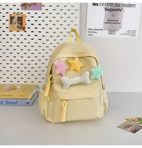 Cute yellow mini backpack for students with plush star bone charms and casual daily design.
