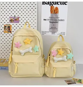 Close-up view of cute yellow backpacks decorated with plush stars and bone toys, aesthetic desk setup.