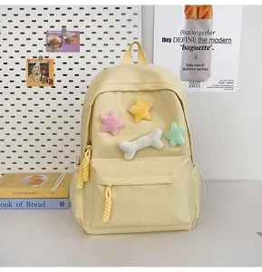 Detail view of a cute yellow backpack with plush star and bone decorations for casual daily use.