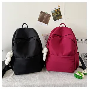 Detailed view of casual nylon backpacks in black and red colors with cute bear pendants.