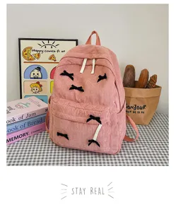 Pink corduroy backpack with cute black bow decorations, casual daily school bag for women.