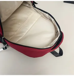 Detailed view of the red backpack interior with beige lining and padded compartment pocket.