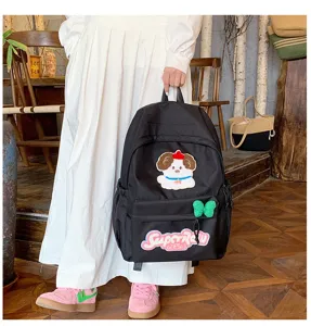 Detailed shot of cute Japanese ins style black backpack with puppy patch and green bow decoration.