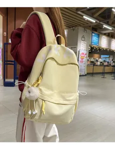 Detailed view of large capacity casual backpack, soft fabric with cute plush pendant and stylish design.