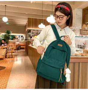Detail view of a dark green corduroy backpack with cute pendant in cozy cafe setting.