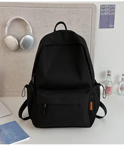 Close-up detail of minimalist solid black school backpack with front pocket and side storage.