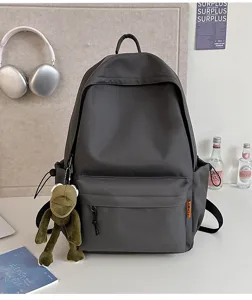 Detail view of the dark grey minimalist backpack with front pocket and cute hanging toy.