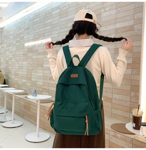 Detail shot of a dark green corduroy backpack worn by a model, showcasing texture and daily design.