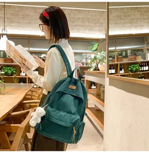 Stylish dark green corduroy backpack with cute bear pendant for daily travel and school use.