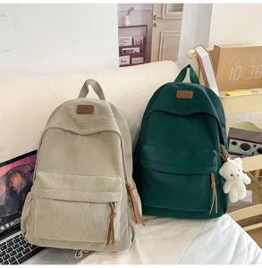 Corduroy backpack detail view, showing soft fabric texture, front pocket and zipper design.