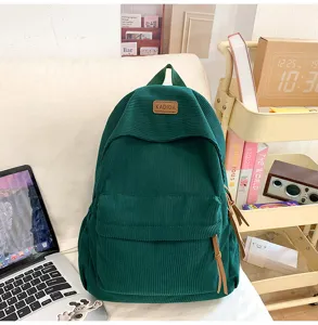 Detailed view of the dark green corduroy backpack in a cozy room setting with daily accessories.