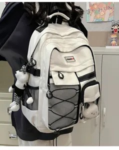 Detail view of the white utility backpack with multiple pockets, mesh, and cute doll pendant.