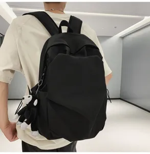 Back view detail of a black casual backpack with a cute monkey keychain, perfect for students.