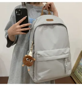 Grey school backpack for students, stylish daily daypack with front pocket and cute pendant.