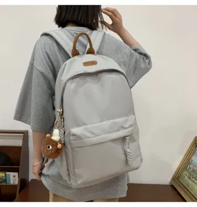 Detail view of the gray casual backpack with a cute bear pendant and top handle in daily use.