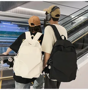 Detailed lifestyle view of minimalist canvas backpacks in black and white worn by couple.