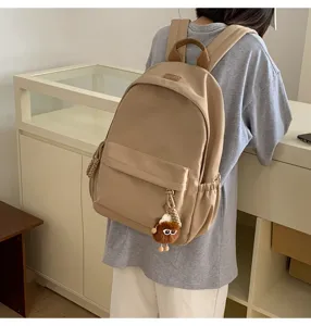Detailed view of casual khaki backpack featuring cute furry keychain and comfortable straps.