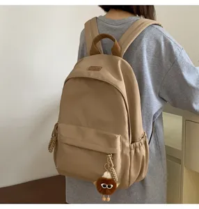 Casual student school backpack in khaki color with cute pendant detail shown now.