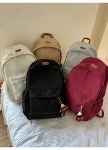 Casual multi-color nylon school backpack with front pocket and cute furry pendant for daily use.
