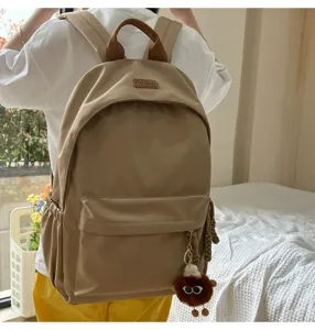 Casual khaki school backpack for daily student commuting with cute plush furry pendant.