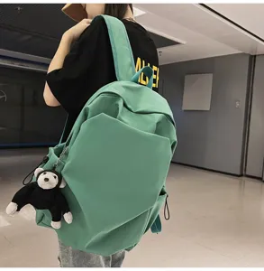 Detail view of the large capacity green casual backpack with hanging plush toy pendant.