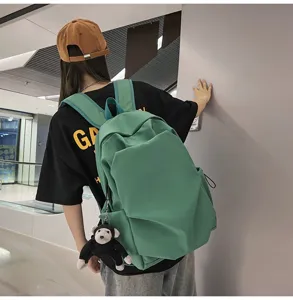 Detail view of the large capacity casual green canvas backpack with cute plush monkey pendant.