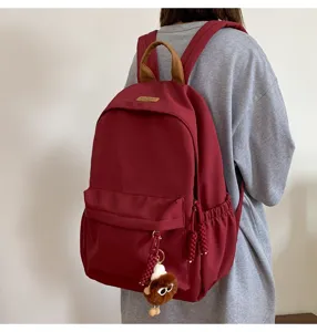 Detailed view of the stylish red canvas backpack with plush charm, casual student daypack.