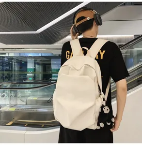 Detail shot of minimalist casual canvas backpack in off-white with cute monkey keychain.