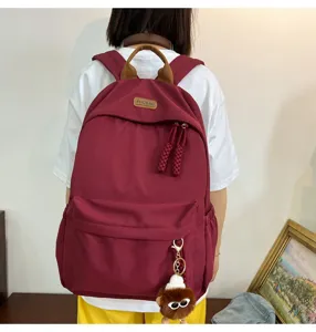 Casual nylon school backpack for women, multi-pocket stylish daypack with cute plush charm.