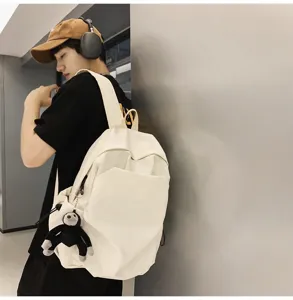 Detailed view of large capacity minimalist casual backpack with cute monkey pendant.