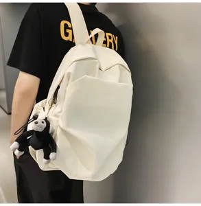 Minimalist large capacity white backpack detail featuring cute plush monkey keychain charm.
