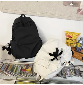 Detail view of minimalist black and white backpacks with cute monkey plush keychain detail.