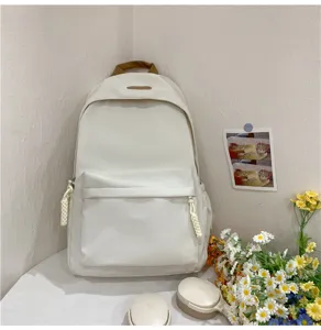 Detailed view of a minimalist white backpack with brown handle and braided zipper pulls.