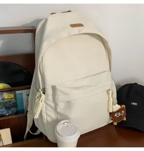 Detailed view of the stylish off-white canvas backpack featuring cute doll pendant and pockets.