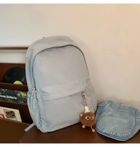 Grey minimalist casual school backpack with spacious compartments and cute plush keychain accessory.