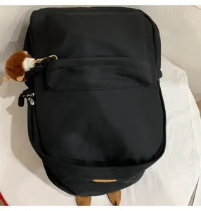 Detail view of black school backpack with cute pendant, casual daily daypack for students.