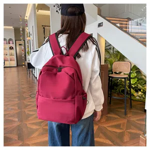 Detailed view of the casual solid color large capacity backpack worn by a model indoors.